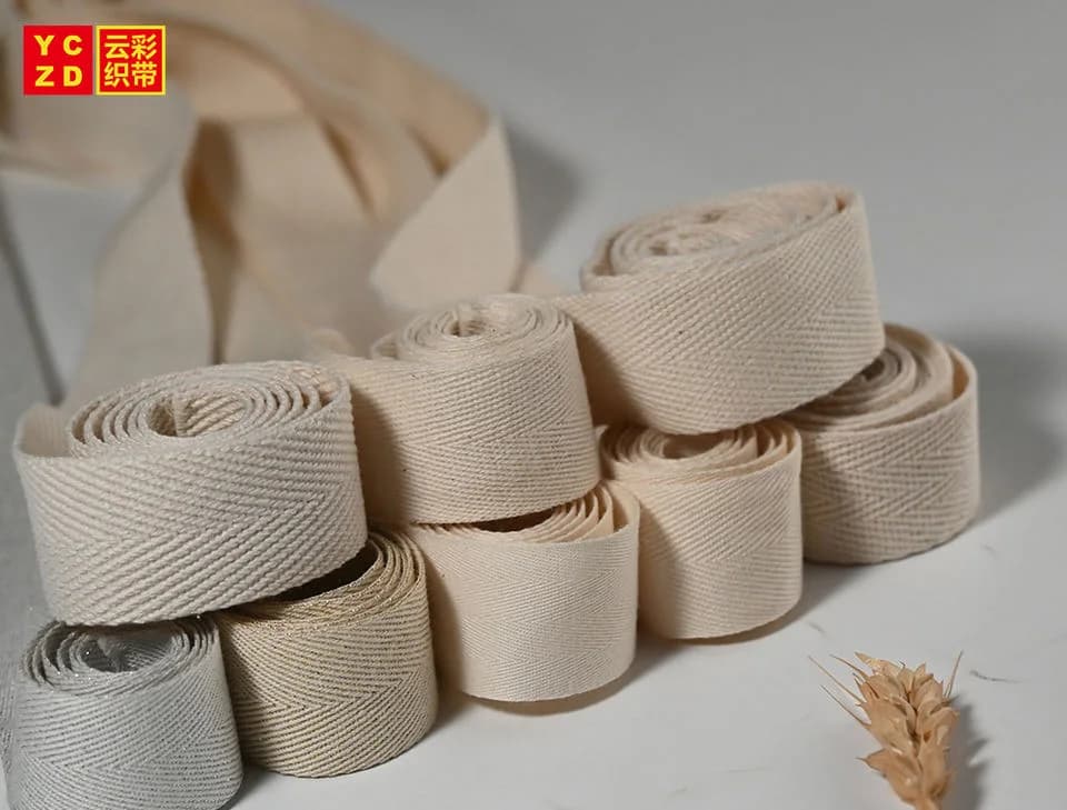 Cream and grey herringbone webbing rolls arranged in a staggered stack