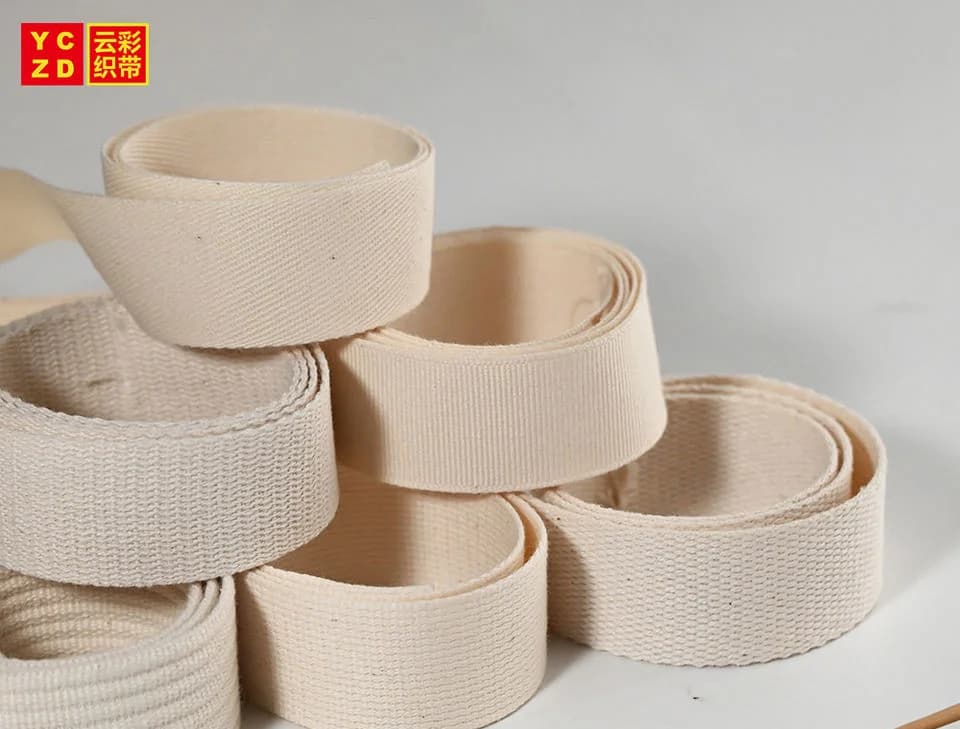 Cream twill webbing rolls arranged beside a dried wheat stem