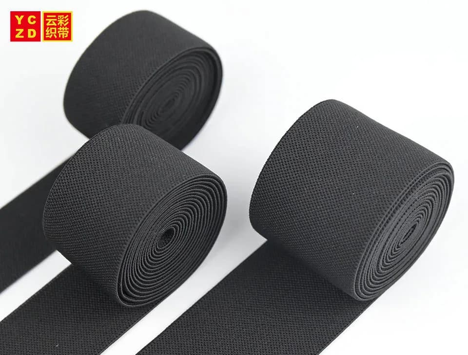 Black textured elastic tapes rolled and folded on grey