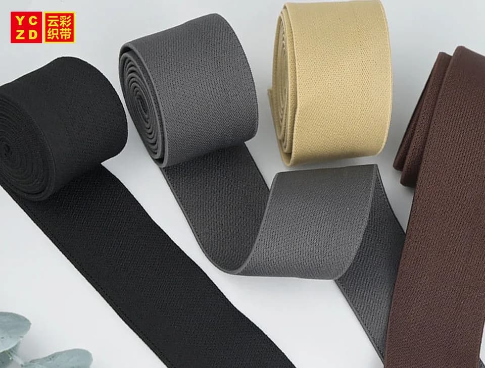 Black, grey, beige and brown elastic tapes arranged in rolls