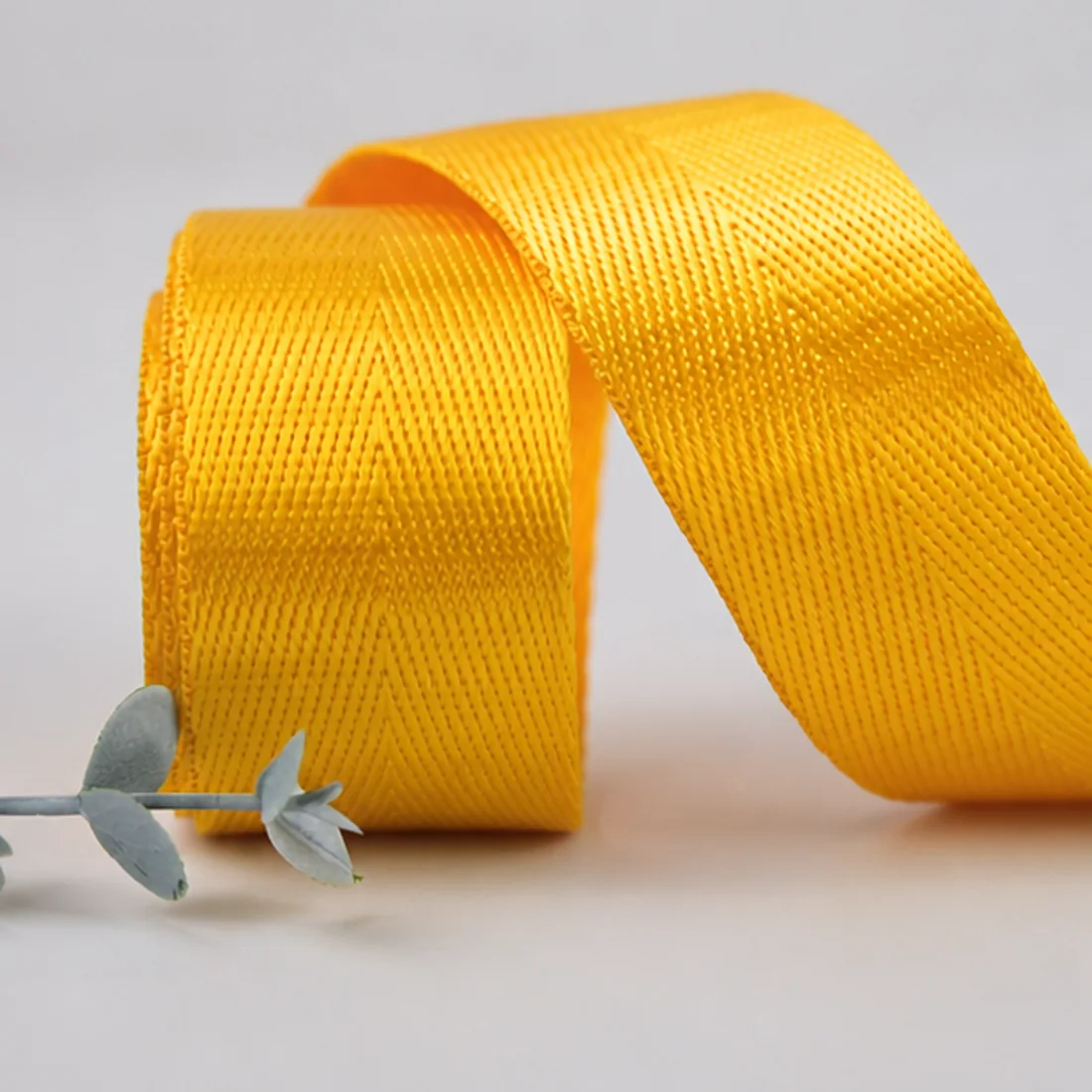 Real yellow woven webbing sample arranged to show face, curve and edge