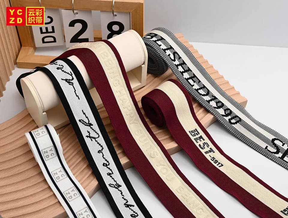 Cream, burgundy and black jacquard tapes hanging over white display bars
