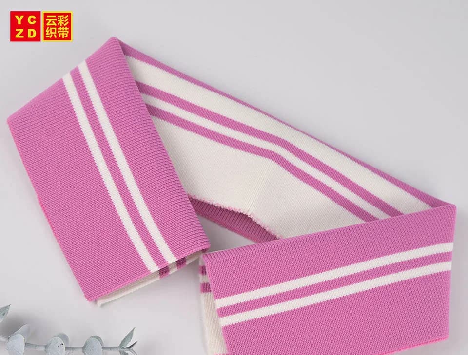 Pink rib-knit collar with two cream stripes on a grey surface