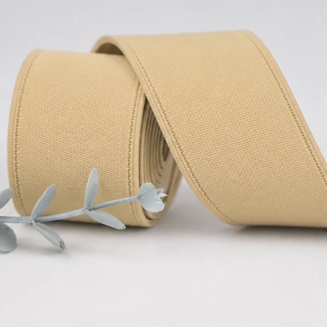 Neutral beige garment elastic with a soft textile face and finished edge