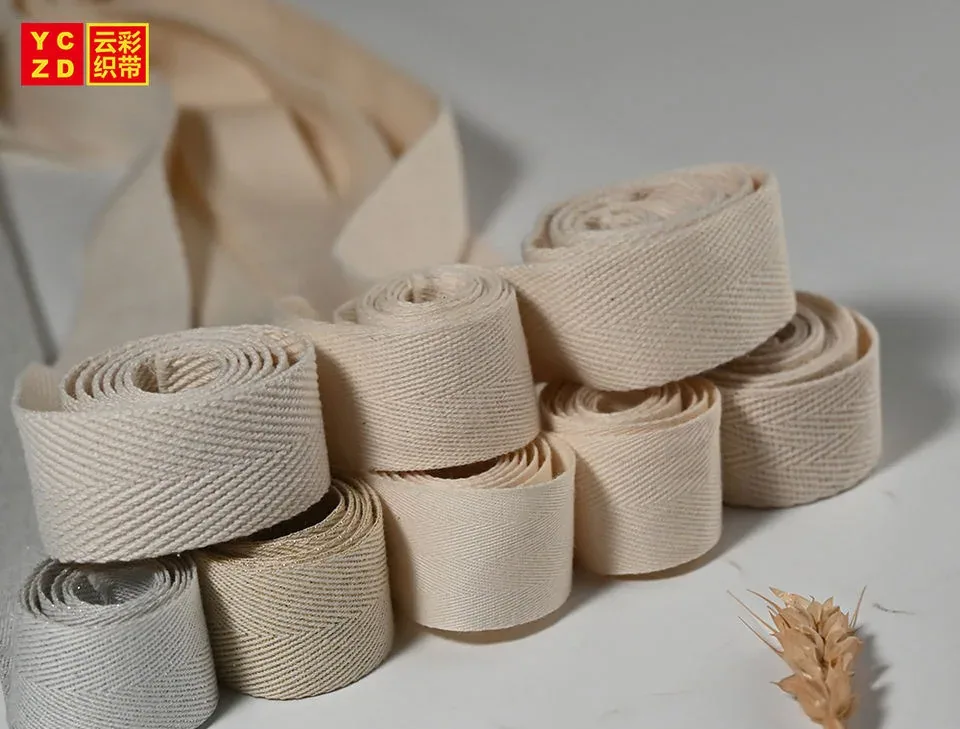 Cream and grey herringbone webbing rolls arranged in a staggered stack