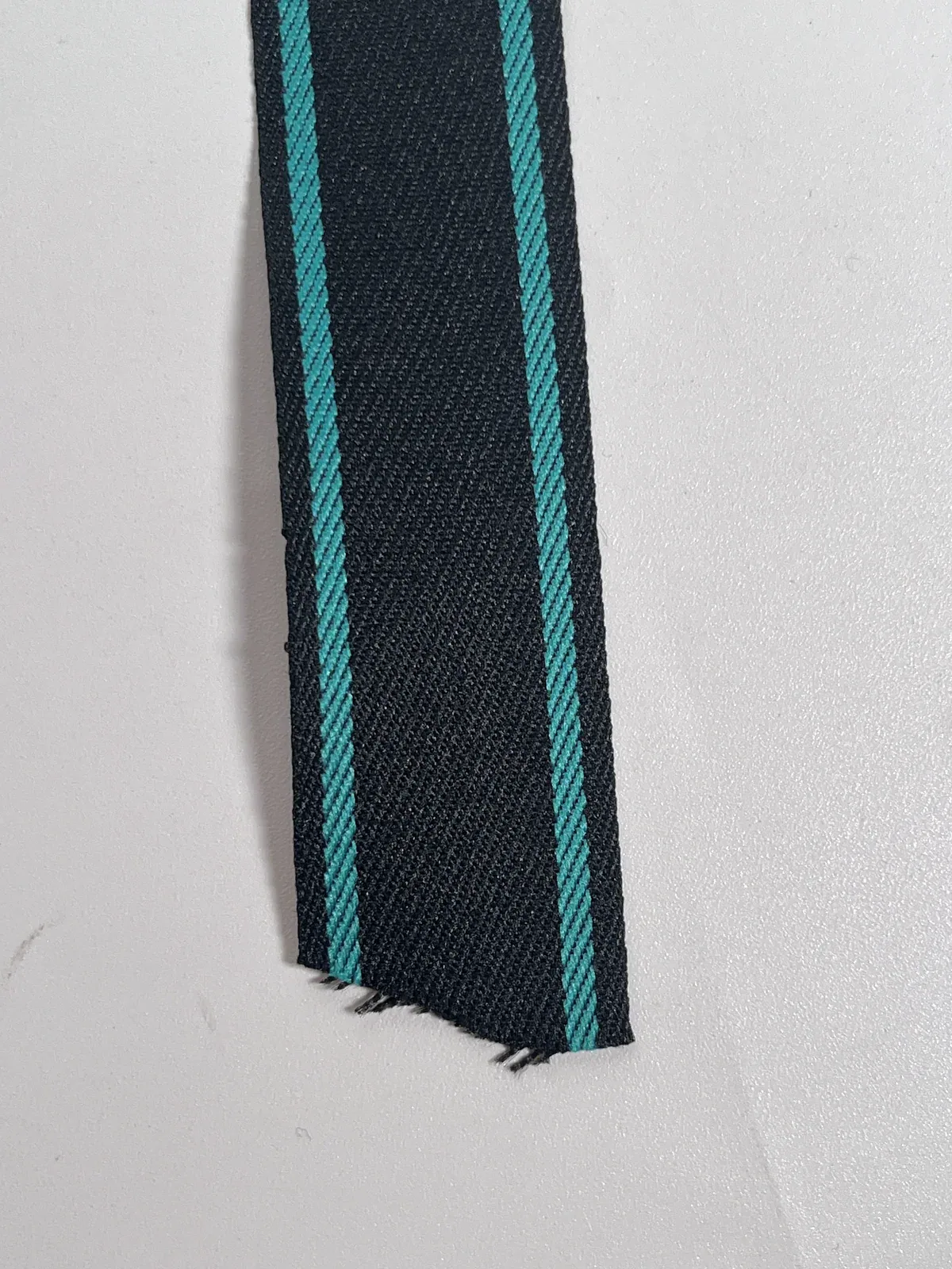 Close view of black tape with turquoise edge stripes and a cut end