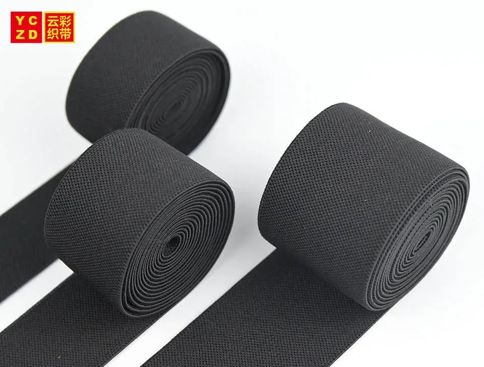 Black textured elastic tapes rolled and folded on grey