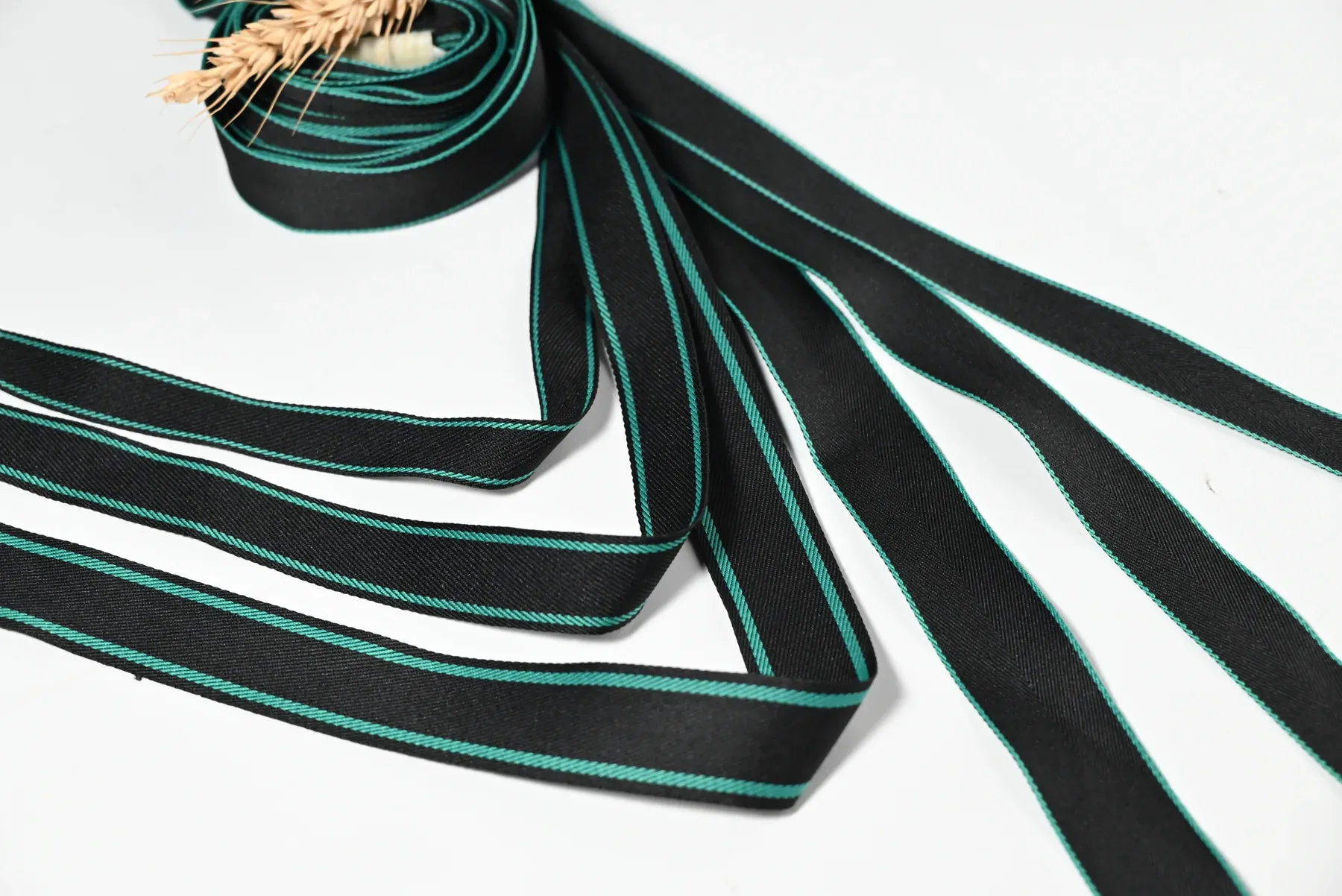 Black tape with turquoise edge stripes arranged in loops on a white surface