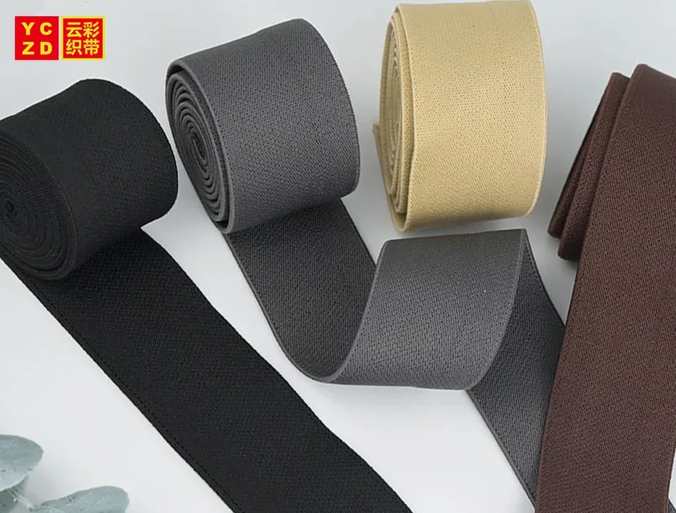 Black, grey, beige and brown elastic tapes arranged in rolls